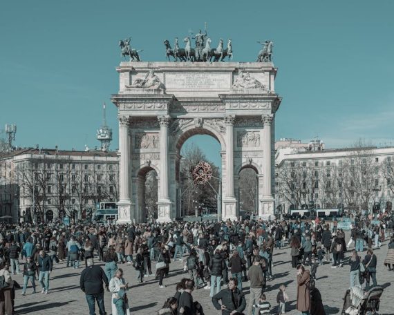 A bustling scene at Arco della Pace in Milan, capturing diverse people under a clear sky.